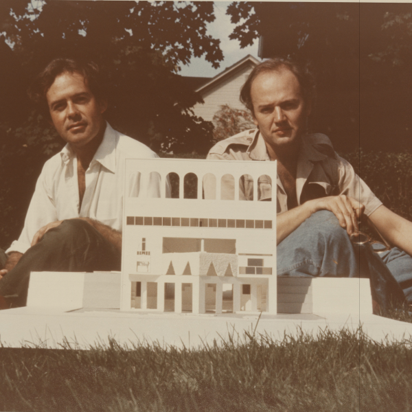 colored image of rodolfo machado and jorge silvetti sitting next to their fountain house model outside in the grass.