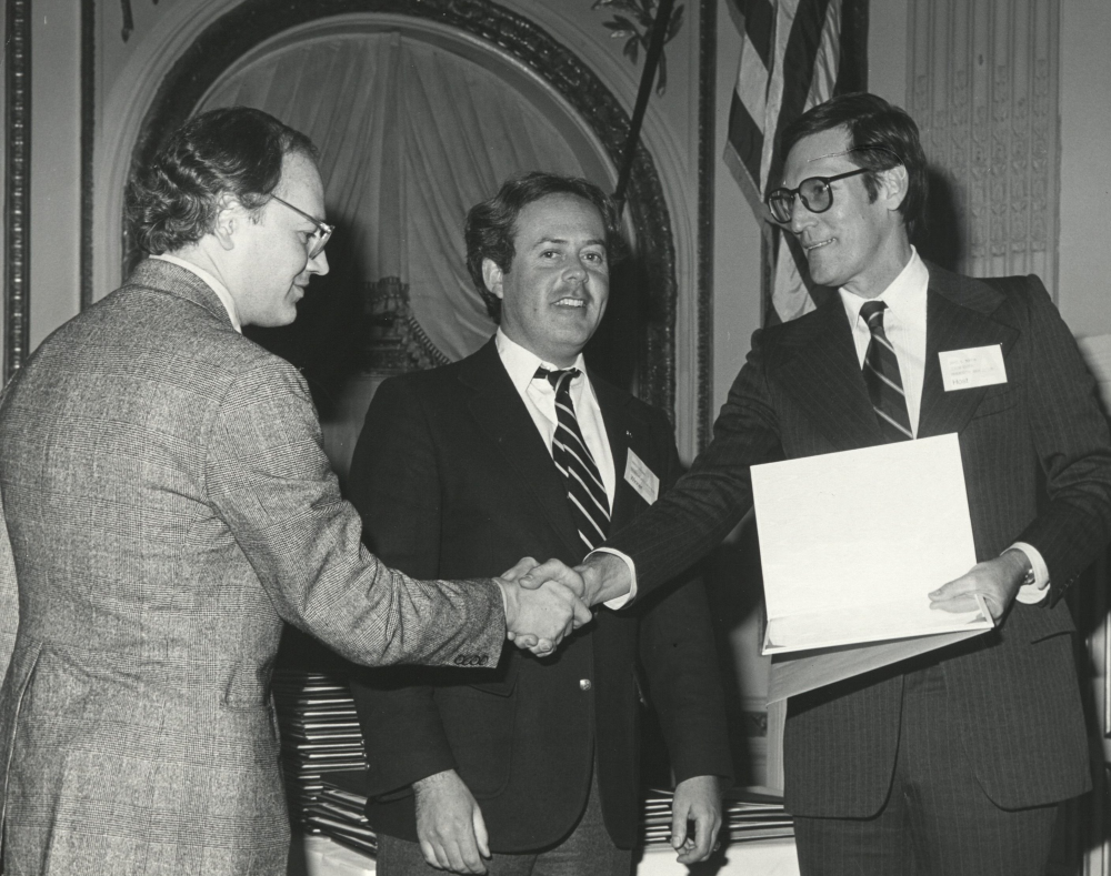 Rodolfo Machado and Jorge Silvetti receiving an award from a presenter on stage.