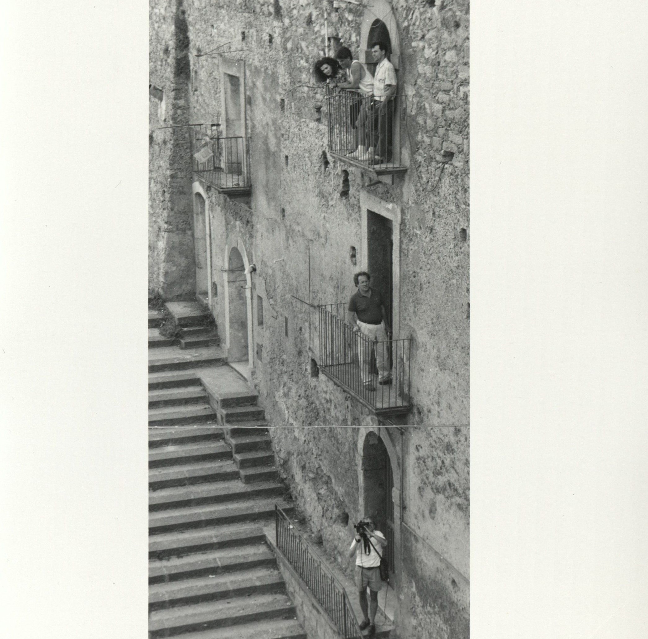 Students stand on three outdoor balconies on a Sicilian building.