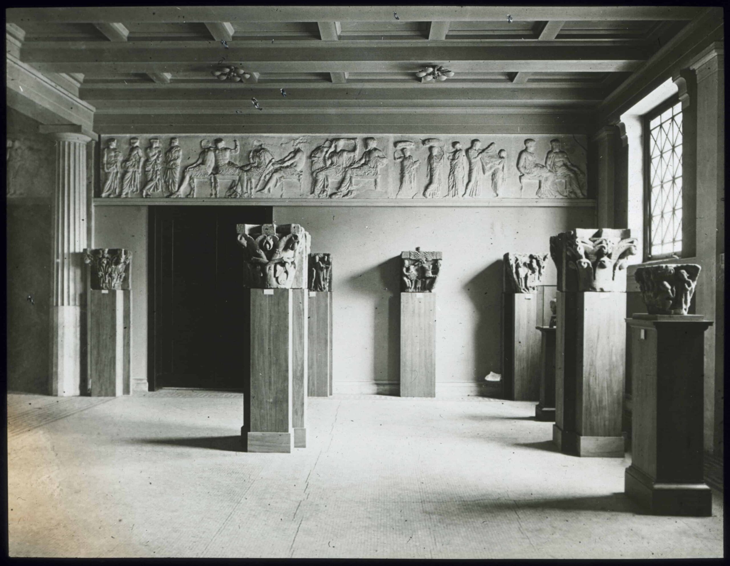 Romanesque capitals displayed on pedestals; plaster casts of the Parthenon frieze on the wall in the Old Fogg Museum (Hunt Hall).